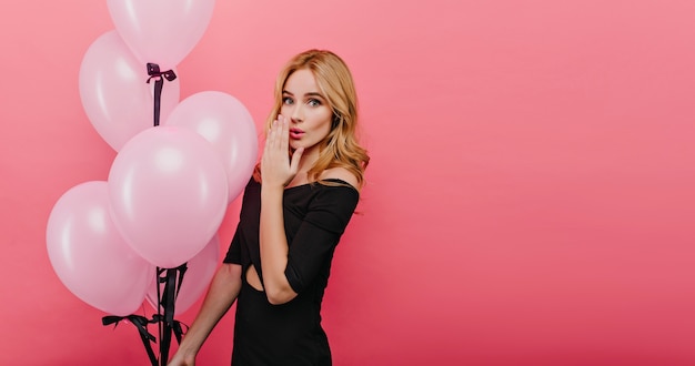 Adorable cumpleañera romántica expresando asombro. Foto de mujer joven guapa con peinado bonito posando con globos.