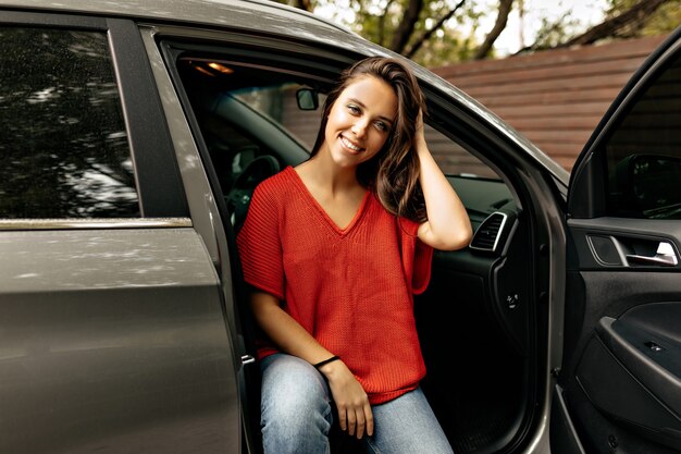 Adorable dama encantadora con sonrisa encantadora posando sentada en el coche