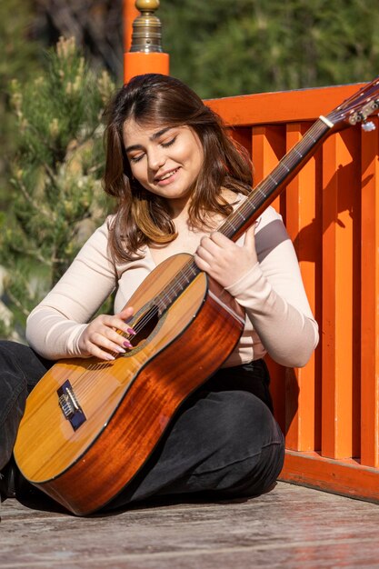 Adorable dulce niña tocando la guitarra en el parque Foto de alta calidad