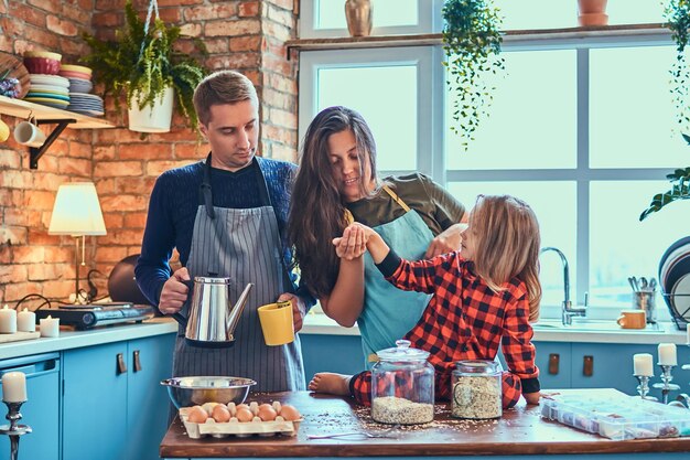 Adorable familia juntos cocinando el desayuno en la cocina estilo loft.