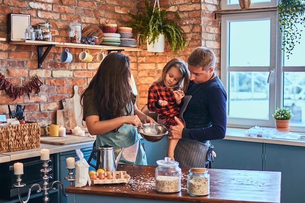 Adorable familia juntos cocinando el desayuno en la cocina estilo loft.