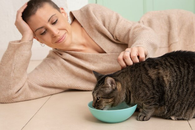 Adorable gatito comiendo junto a su dueño