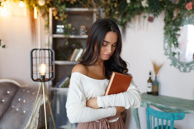 Adorable hermosa niña abrazó su libro y miró hacia abajo Foto de alta calidad