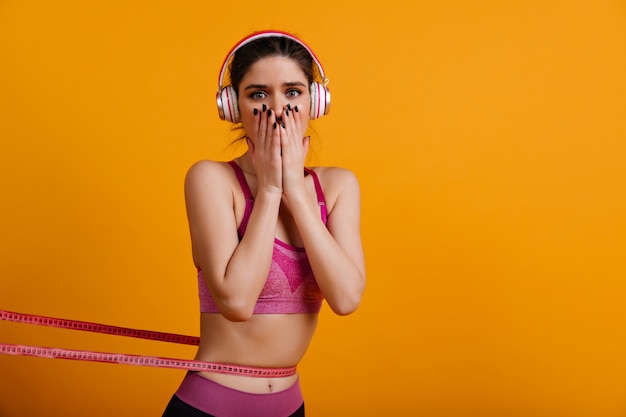 Adorable joven en auriculares midiendo su cintura