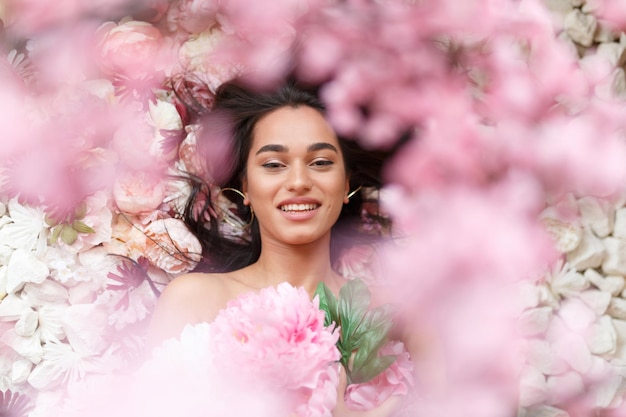 Adorable joven modelo sonriendo en flores de colores Foto de alta calidad