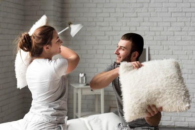 Adorable joven y mujer lucha de almohadas