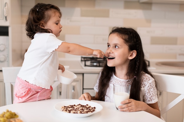 Adorable jovencita alimentando a su hermana