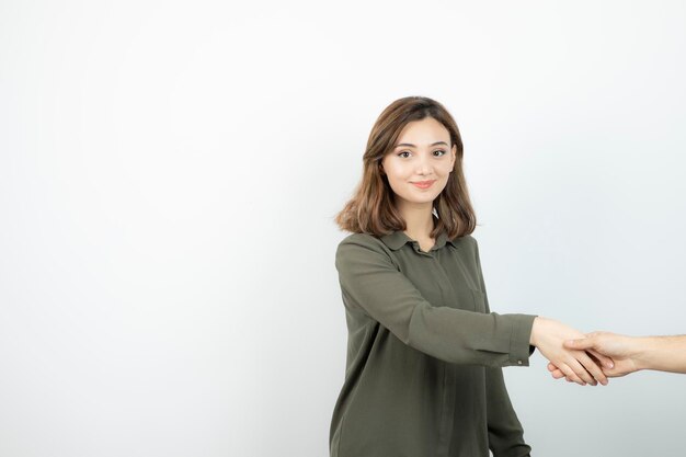 Adorable mujer joven en ropa casual estrechando la mano con alguien. foto de alta calidad