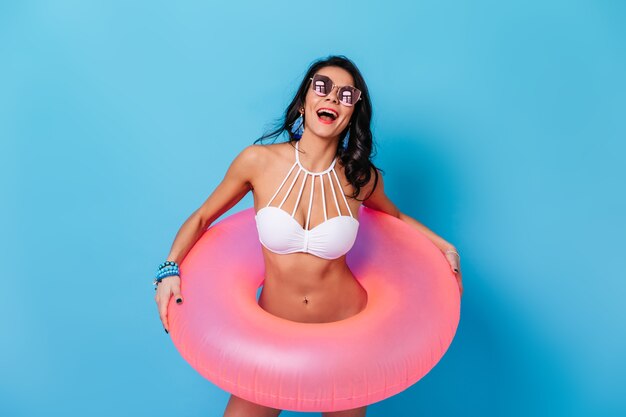 Adorable mujer posando con círculo de natación rosa