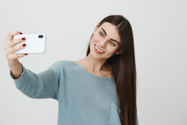 Adorable mujer sonriente tomando selfie en smartphone