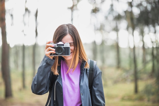 Adorable mujer tomando fotos en el bosque