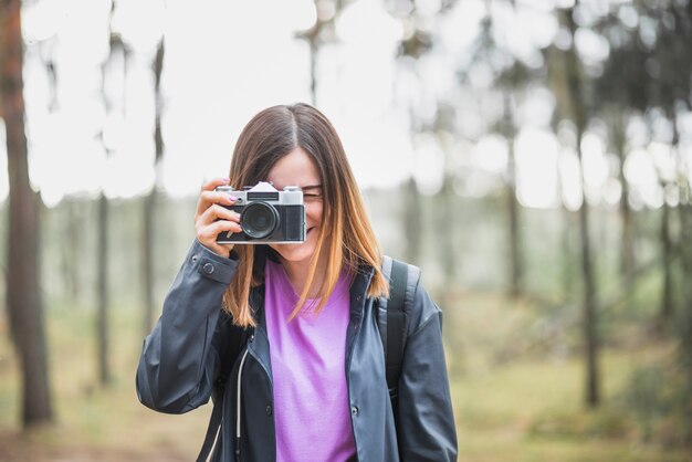 Adorable mujer tomando fotos en el bosque