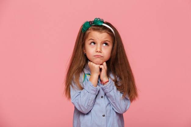 Adorable niña apoyando su cabeza con los puños molestos o soñando