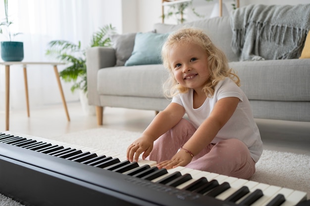 Adorable niña aprendiendo a tocar el piano en casa