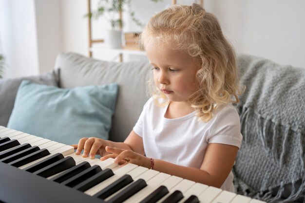 Adorable niña aprendiendo a tocar el piano en casa