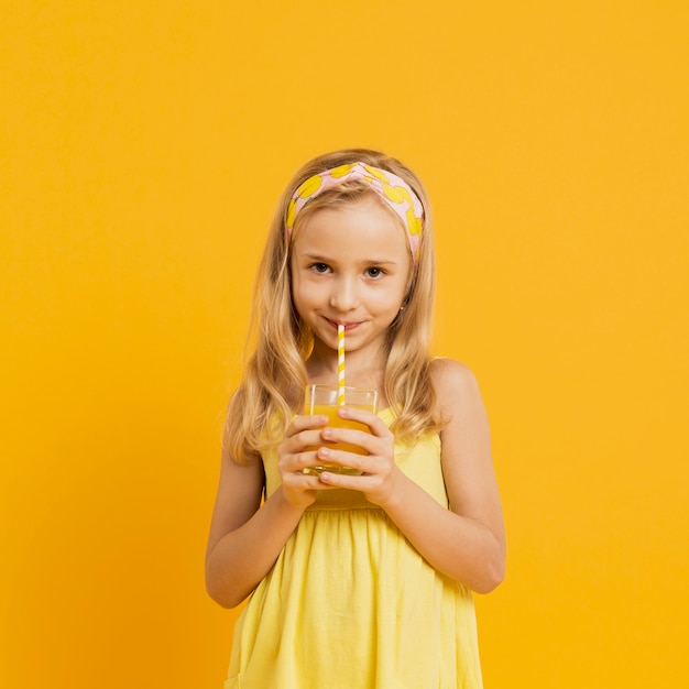 Adorable niña bebiendo limonada con paja
