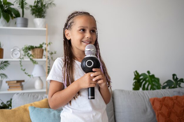 Adorable niña cantando en un micrófono en casa