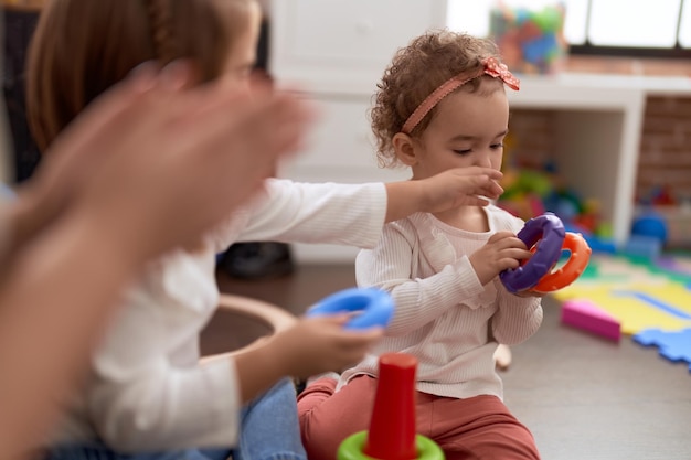 Foto gratuita adorable niña caucásica jugando con aros sentados en el piso en el jardín de infantes