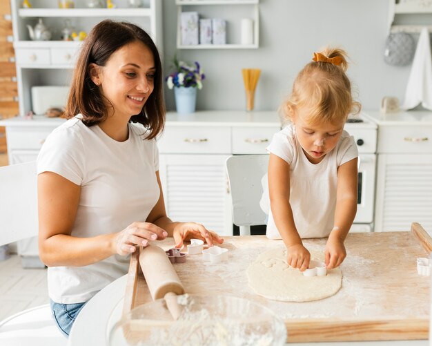 Adorable niña cortando masa para galletas