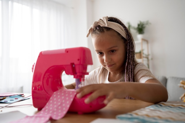 Foto gratuita adorable niña cosiendo ropa a mano