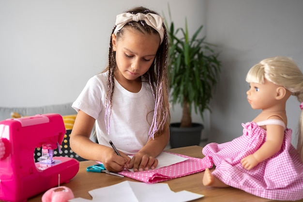 Adorable niña cosiendo ropa a mano