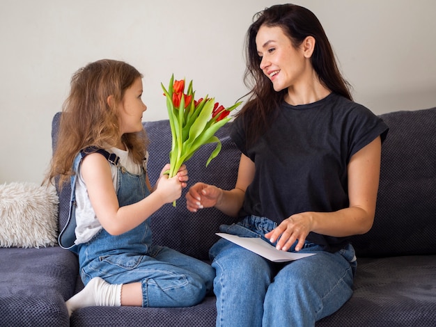 Adorable niña dando flores a la madre