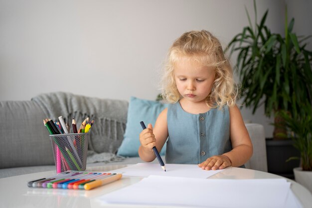 Adorable niña dibujando en papel en casa