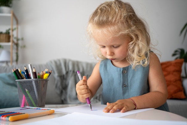 Adorable niña dibujando en papel en casa