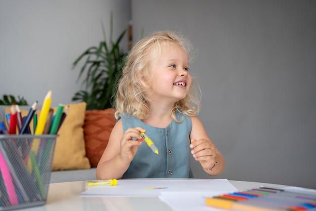 Adorable niña dibujando en papel en casa