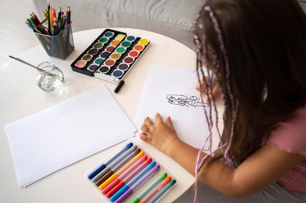 Adorable niña dibujando en papel en casa