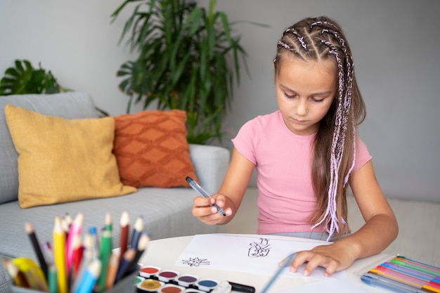 Adorable niña dibujando en papel en casa