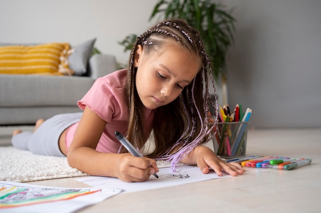 Adorable niña dibujando en papel en casa