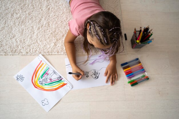 Adorable niña dibujando en papel en casa