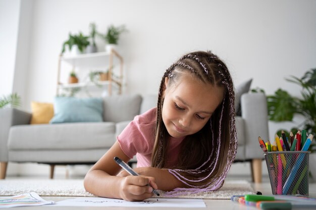 Adorable niña dibujando en papel en casa