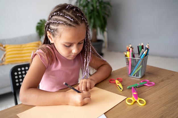 Adorable niña dibujando en papel en casa