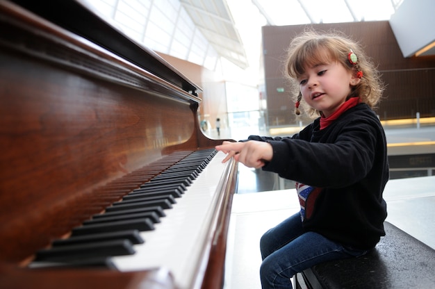 Adorable niña se divierte tocando el piano