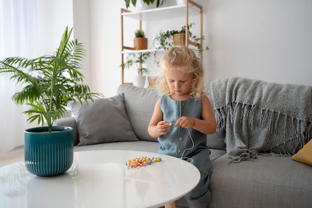 Adorable niña haciendo accesorios con diferentes bolas de colores