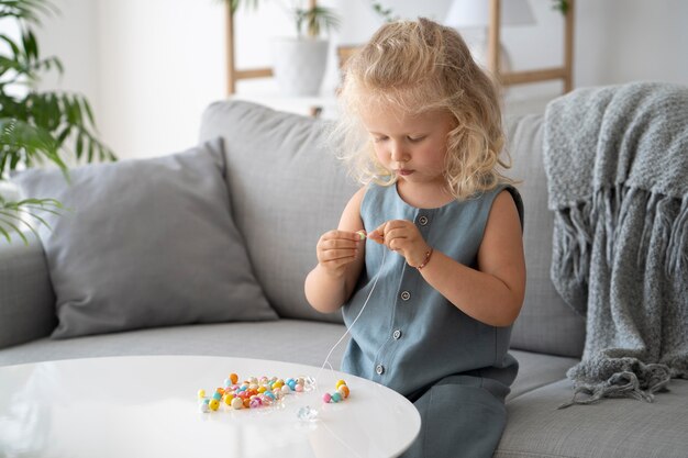 Adorable niña haciendo accesorios con diferentes bolas de colores