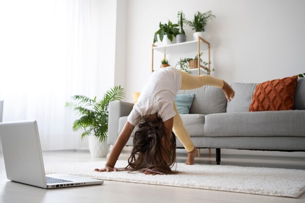 Adorable niña haciendo yoga en casa