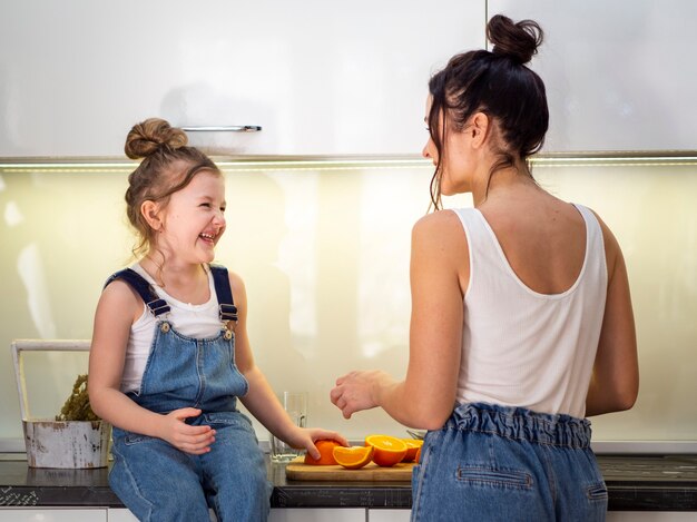 Adorable niña jugando con la madre en la cocina