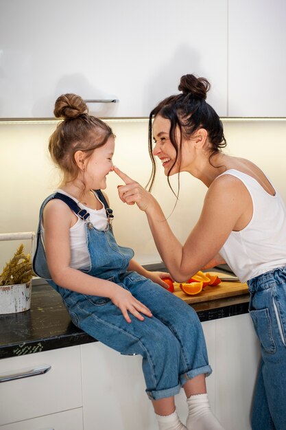 Adorable niña y madre juntas en la cocina