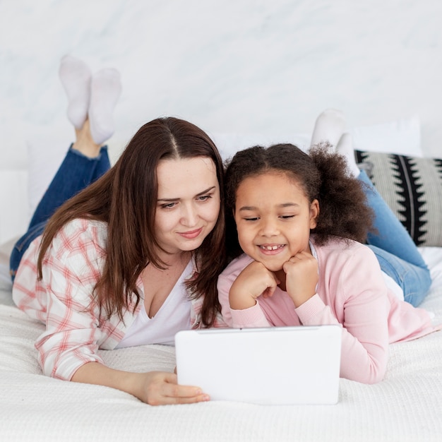 Adorable niña mirando dibujos animados con madre