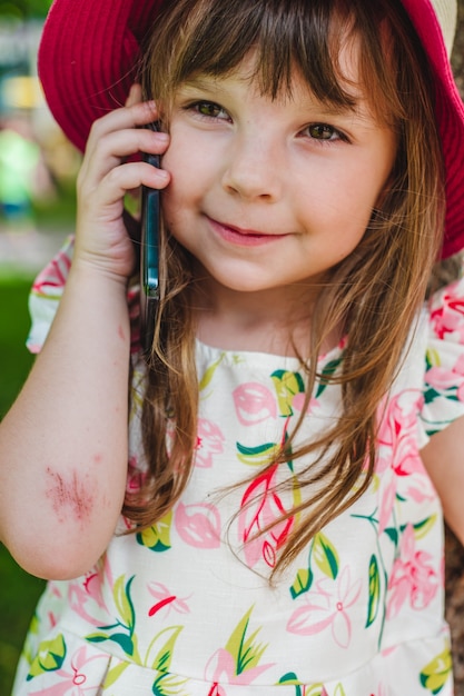 Adorable niña pequeña hablando por un teléfono móvil