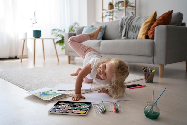 Adorable niña pintando sobre papel en casa