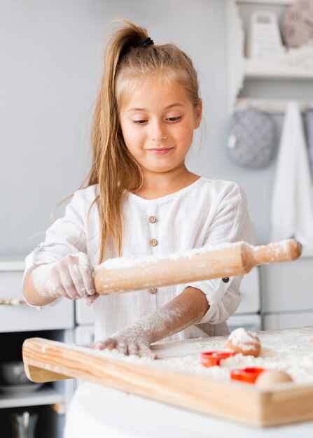 Adorable niña con rodillo de cocina