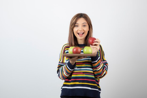 Adorable niña en ropa casual con manojo de manzanas.