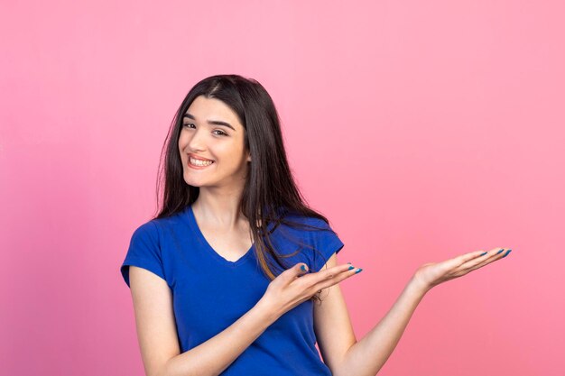 Adorable niña señalando sus manos a un lado y sonriendo a la cámara Foto de alta calidad