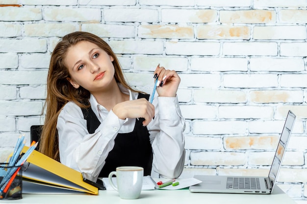 Una adorable niña sentada en el escritorio y pensando foto de alta calidad