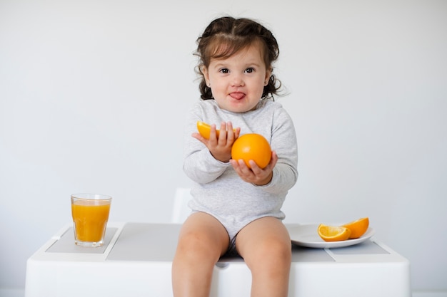 Adorable niña sentada y mostrando sus naranjas
