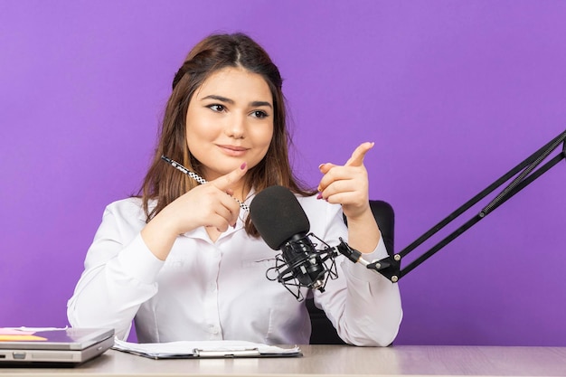 Adorable niña sentada en la oficina y señalando con el dedo a un lado Foto de alta calidad